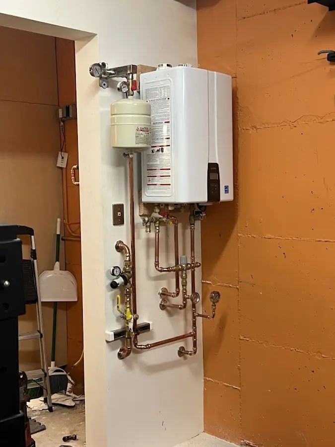 Plumbing technician inspecting water heater connections in Page